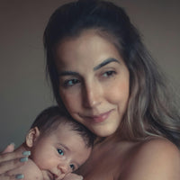 Woman holding a baby wrapped in a white blanket