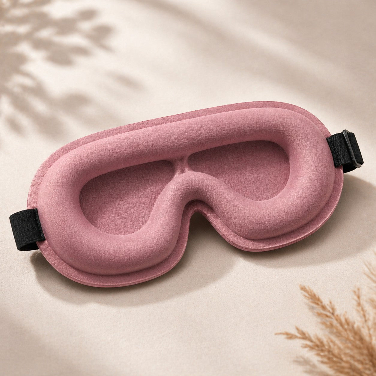 SlumberHush DeepShield pink contoured sleep mask with adjustable black strap, made of soft plush material.
