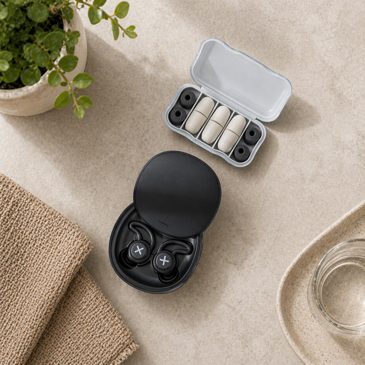 SlumberHush QuietSeal earplugs in black with white cross detail, shown with a travel case containing spare ear tips.
