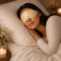 SlumberHush WarmEye steam mask in yellow floral pattern, worn by a woman sleeping peacefully in bed.